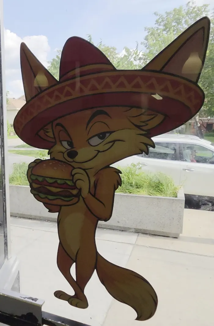 A cartoon fox in a patterned red sombrero holding a burger, a decal on the La Zone 23 door